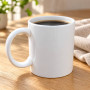 Vit mugg utan text eller motiv med kaffe på ett träbord bredvid en beige servett