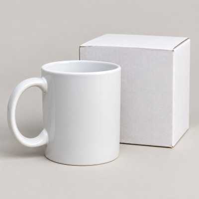 Vit kaffe- och temugg utan motiv bredvid medföljande vit ask